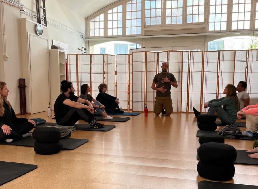 James guiding a group seated on mats during a workshop